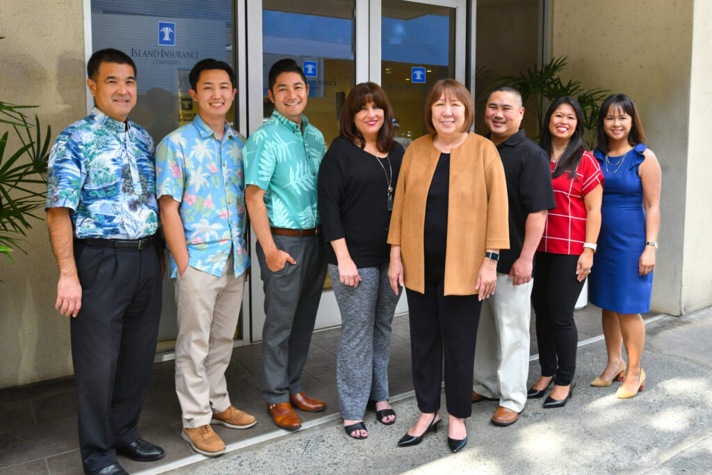 employees smiling in front of Island Insurance building